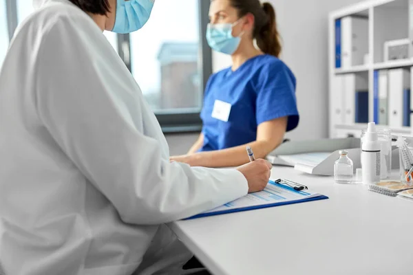 Doctor with clipboard and nurse at hospital — Stock Photo, Image