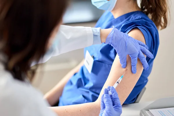 Médico con jeringa vacunando al trabajador médico — Foto de Stock