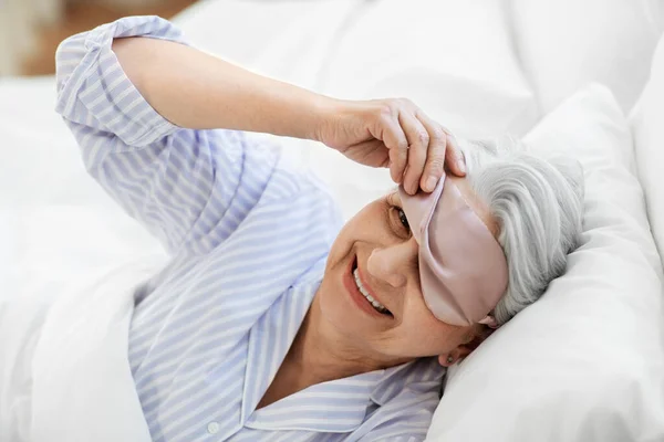 Wanita senior dengan penutup mata tidur di tempat tidur di rumah — Stok Foto