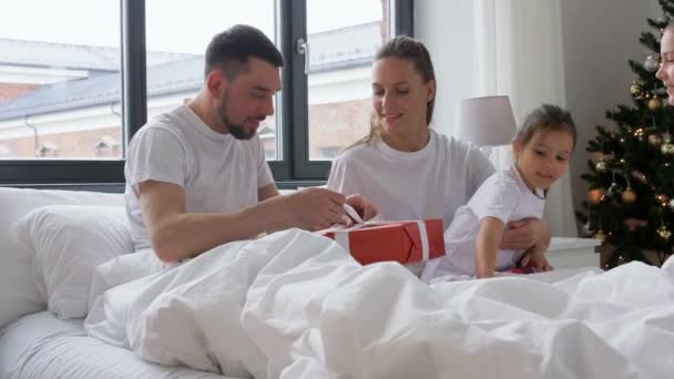 Família feliz com presentes de Natal na cama em casa — Vídeo de Stock