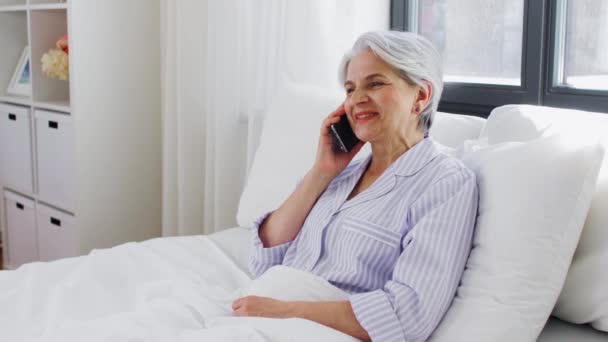 Senior femme appelant sur smartphone dans le lit à la maison — Video
