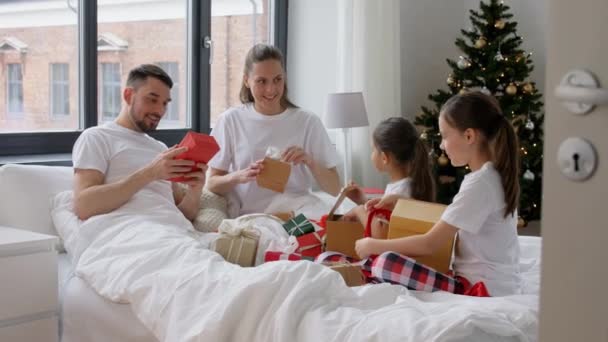 Gelukkig gezin met kerstcadeaus in bed thuis — Stockvideo