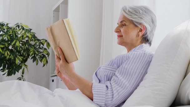 Senior femme lecture livre dans lit à la maison chambre — Video