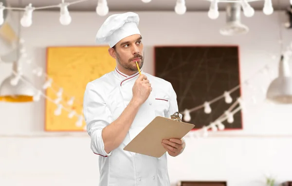 Chef masculino pensante con portapapeles en el restaurante —  Fotos de Stock