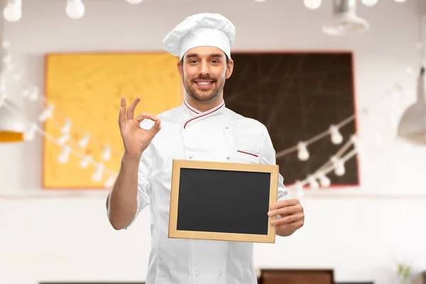 Feliz sorrindo chef masculino mostrando quadro-negro — Fotografia de Stock
