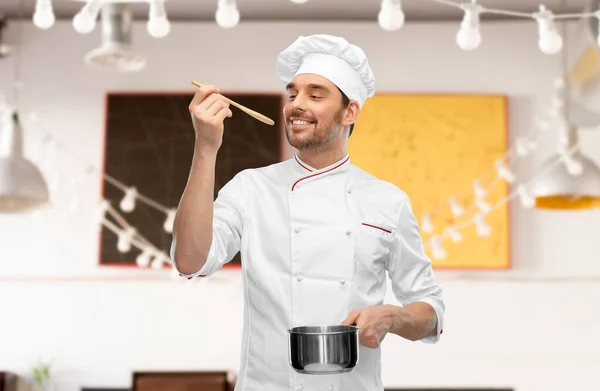 Happy smiling male chef with saucepan tasting food — Stock Photo, Image