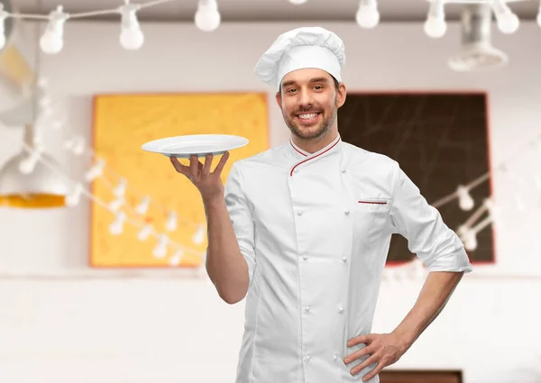 Happy smiling male chef holding empty plate — Stock Photo, Image