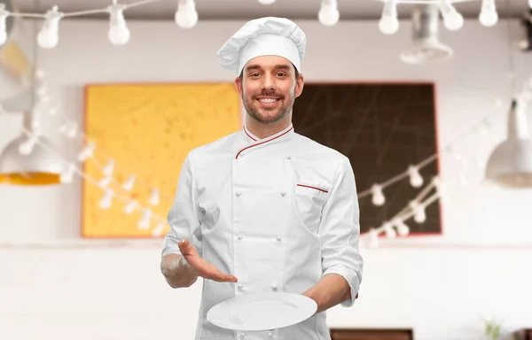 Happy smiling male chef holding empty plate — Stock Photo, Image