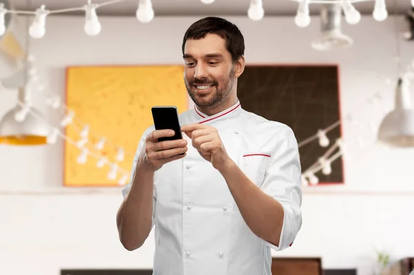 Feliz chef masculino sonriente con teléfono inteligente — Foto de Stock