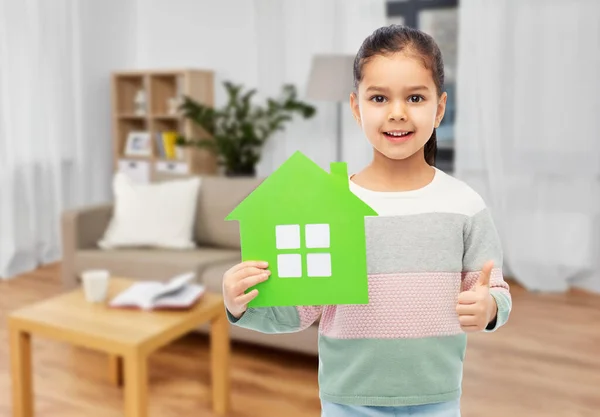 Smiling little girl with green house icon at home — Stock Photo, Image