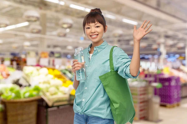 Žena s taškou na nákup potravin a skleněné láhve — Stock fotografie