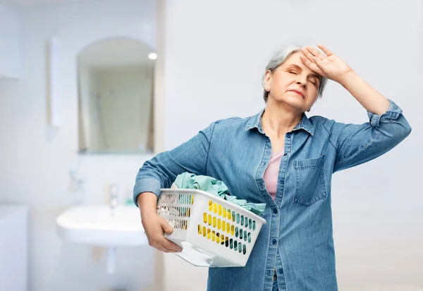 Stanca donna anziana con cesto della lavanderia — Foto Stock