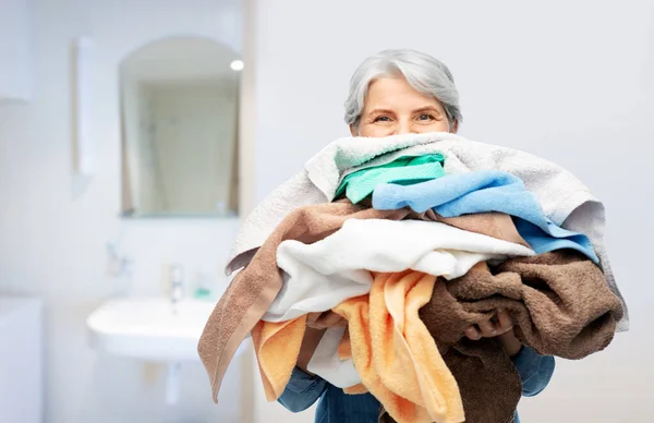 Banyo havlusu yığınıyla yaşlı bir kadın. — Stok fotoğraf