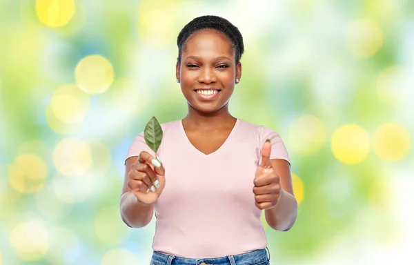 Χαμογελαστή Αφροαμερικανή γυναίκα που κρατάει πράσινο φύλλο — Φωτογραφία Αρχείου