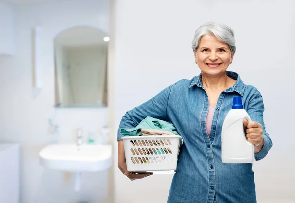 Lächelnde Seniorin mit Wäschekorb Stockfoto