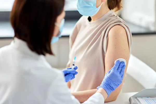 Kvinnlig läkare med spruta vaccinerande patient — Stockfoto