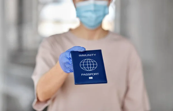 Woman in mask and gloves holding immunity passport — Stock Photo, Image