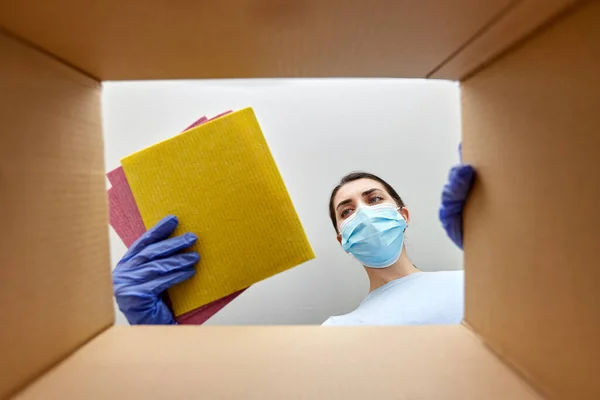 Vrouw in masker het nemen van schoonmaakmiddelen uit doos — Stockfoto