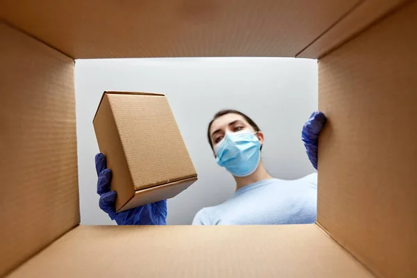 Mujer en máscara tomando caja de paquete —  Fotos de Stock