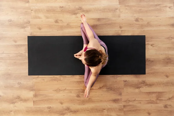 Vrouw doet yoga oefening op mat in studio — Stockfoto