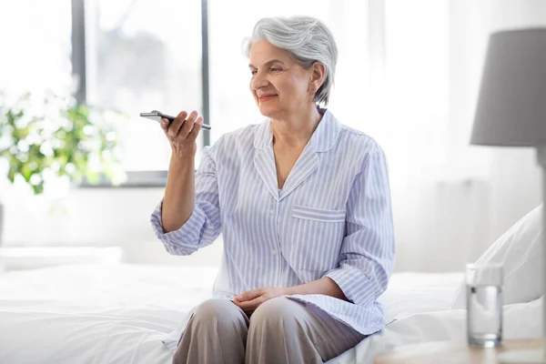 Gelukkig senior vrouw opname stem op smartphone — Stockfoto