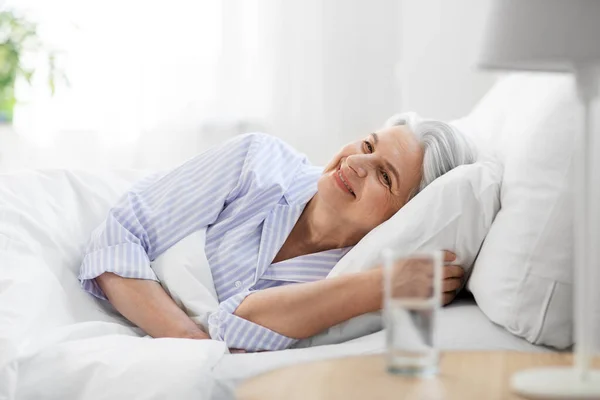 Mulher sênior feliz deitado na cama em casa quarto — Fotografia de Stock