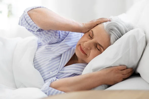 Mulher idosa irritada com dor de cabeça na cama em casa — Fotografia de Stock