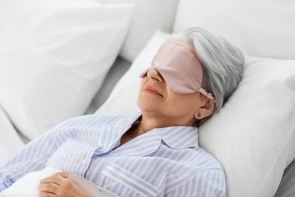 Senior kvinna med ögonmask sover i sängen hemma — Stockfoto