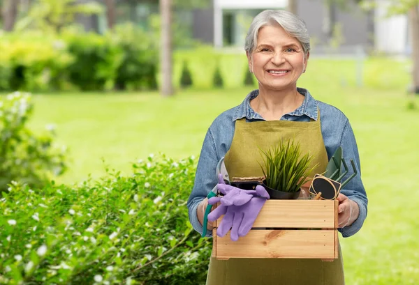 Sonriente mujer mayor con herramientas de jardín en caja — Foto de Stock