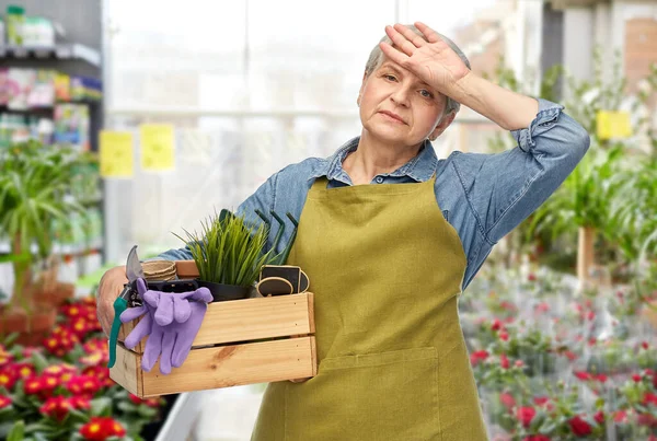 tired senior woman with garden tools in box