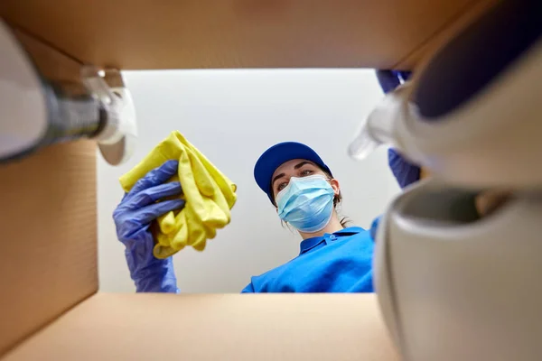 Vrouw in masker verpakking schoonmaakmiddelen in doos — Stockfoto