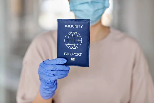 Mulher em máscara e luvas segurando passaporte imunidade — Fotografia de Stock