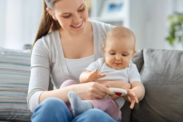 Mutter und kleines Baby spielen zu Hause mit Rassel — Stockfoto