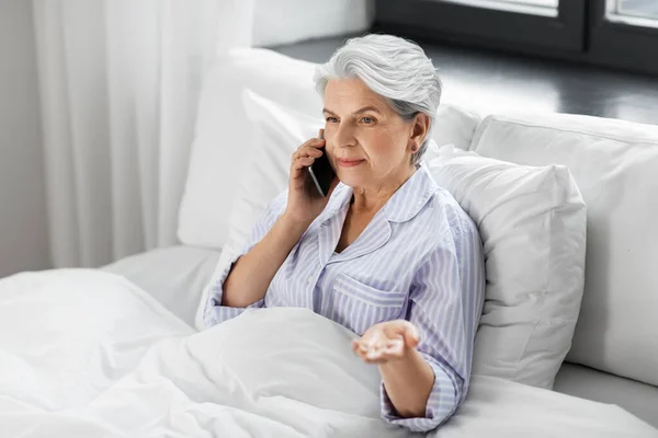 Senior woman calling on smartphone in bed at home — Stock Photo, Image