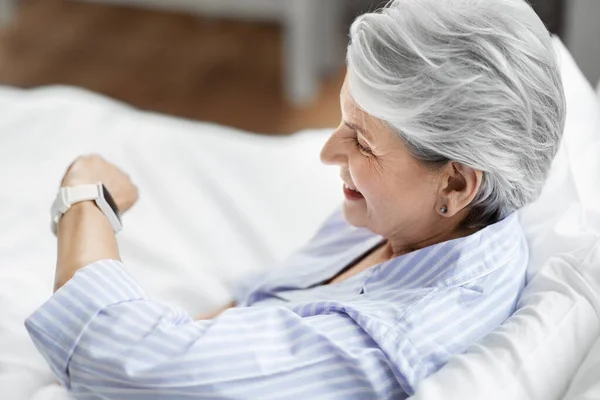 Gelukkig senior vrouw zitten in bed thuis slaapkamer — Stockfoto