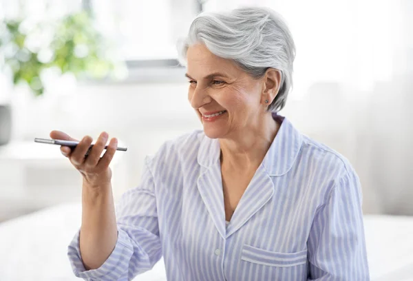 Счастливая пожилая женщина записывает голос на смартфон — стоковое фото
