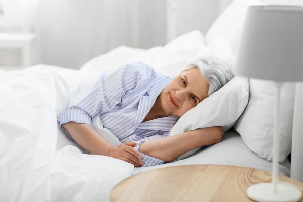 Donna anziana sdraiata a letto a casa camera da letto — Foto Stock