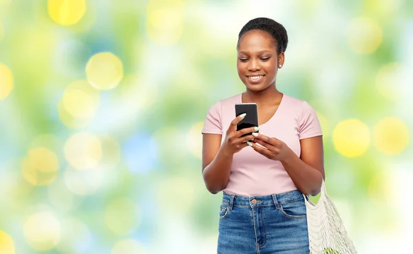 Woman with smartphone and food in string bag — Stock Photo, Image