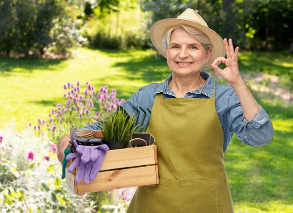 Mulher velha com ferramentas de jardim na caixa mostrando ok — Fotografia de Stock