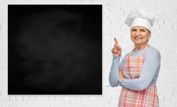 Mujer mayor o chef señalando con el dedo a la pizarra — Foto de Stock