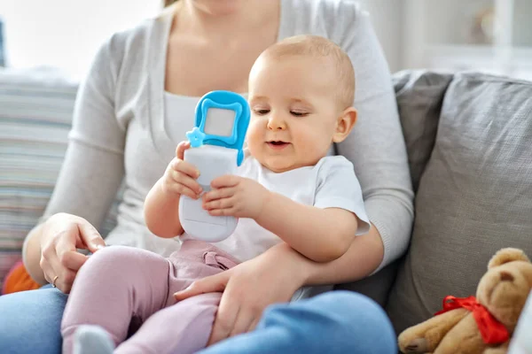 Madre con el bebé jugando con el teléfono de juguete en casa —  Fotos de Stock