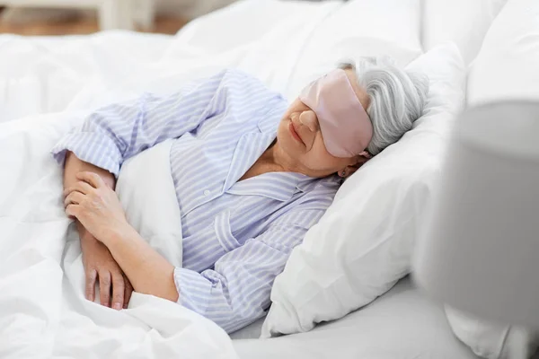 Senior kvinna med ögonmask sover i sängen hemma — Stockfoto