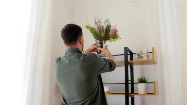 Mann schmückt Haus mit Blume oder Zimmerpflanze — Stockvideo