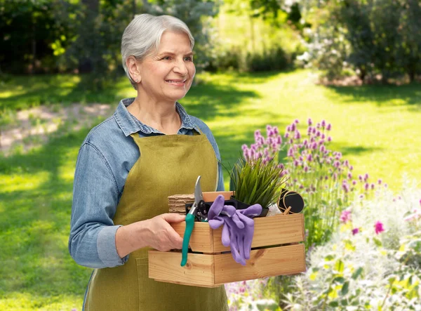 Mulher sênior sorridente com ferramentas de jardim na caixa — Fotografia de Stock