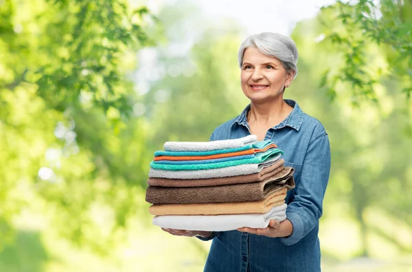 Glimlachende senior vrouw met schone handdoeken — Stockfoto