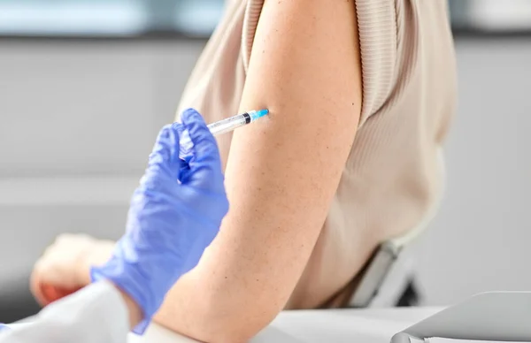 Vrouwelijke arts met injectiespuit vaccinerende patiënt — Stockfoto