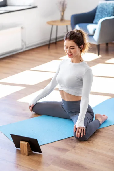 Giovane donna con tablet pc facendo yoga a casa — Foto Stock