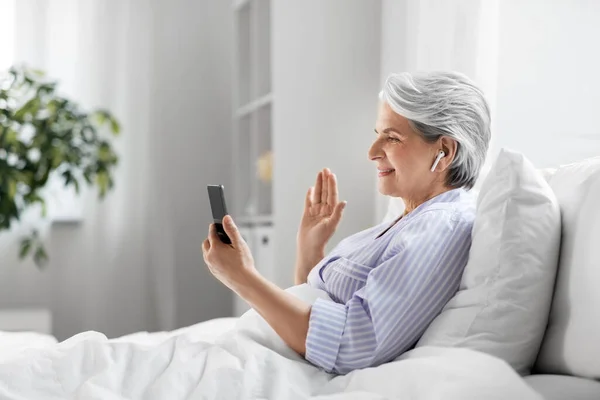Starší žena s telefonem s videohovory v posteli — Stock fotografie