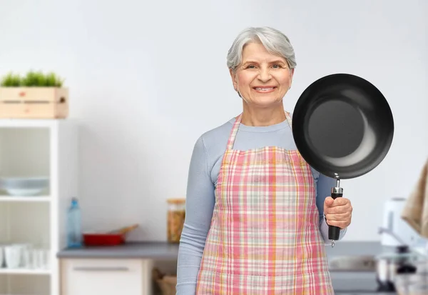 Mosolygós idős nő sütő serpenyőben a konyhában — Stock Fotó