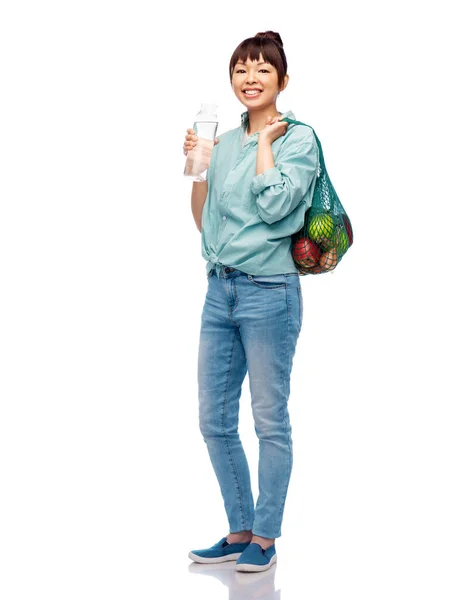 Femme avec de la nourriture dans un sac à ficelle et bouteille en verre — Photo